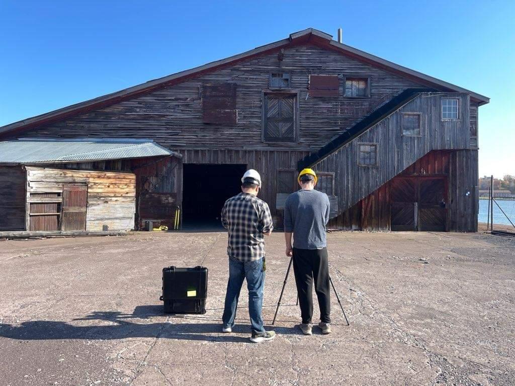 Surveyors using scanning equipment in front of building